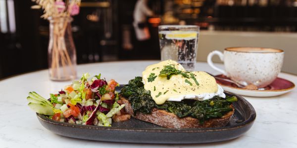 Pochierte Eier mit Spinat und Sauce Hollandaise auf geröstetem Brot, dazu eine Salatbeilage.