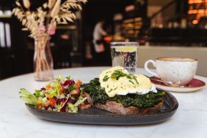 Pochierte Eier mit Spinat und Sauce Hollandaise auf geröstetem Brot, dazu eine Salatbeilage