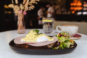 Pochierte Eier mit Schinken und Sauce Hollandaise auf Brot, dazu eine Salatbeilage