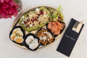 Eine Servierplatte mit Avocado-Schnittchen, Räucherlachs, Eiern, Kichererbsen und Salat im Café Jolie.