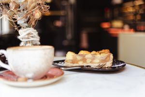Ein Stück Apfelkuchen, im Vordergrund eine Kaffeetasse