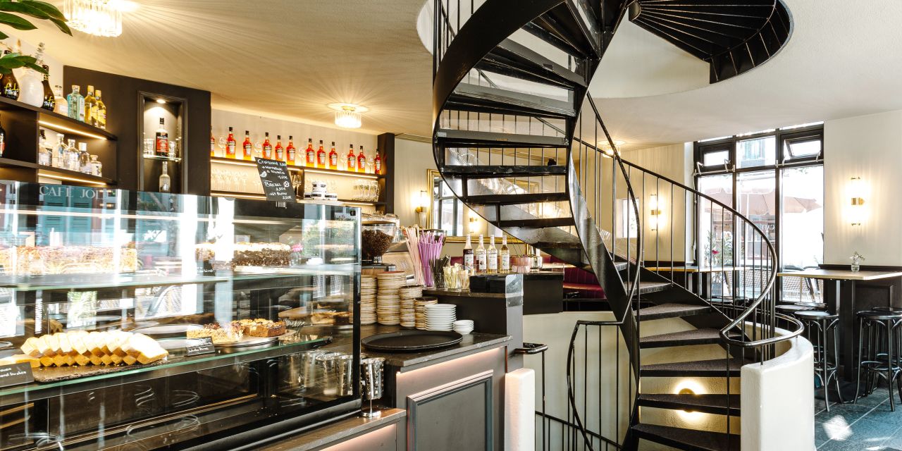 Blick auf die Theke und geschwungene Wendeltreppe in Café Jolie