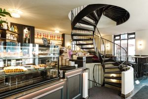 Blick auf die Theke und geschwungene Wendeltreppe in Café Jolie