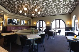 Bestuhlter Innenraum mit Tischen im Obergeschoss mit Blick auf geschwungene Fenster