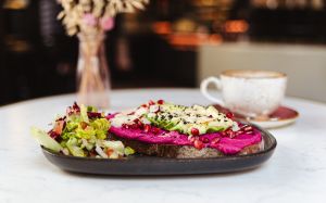 Brot mit Rote-Bete-Aufstrich, Avocado und Granatapfelkernen, dazu eine Salatbeilage