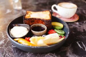 French Toast mit frischen Früchten, Creme und Sirup auf einem dunklen Teller